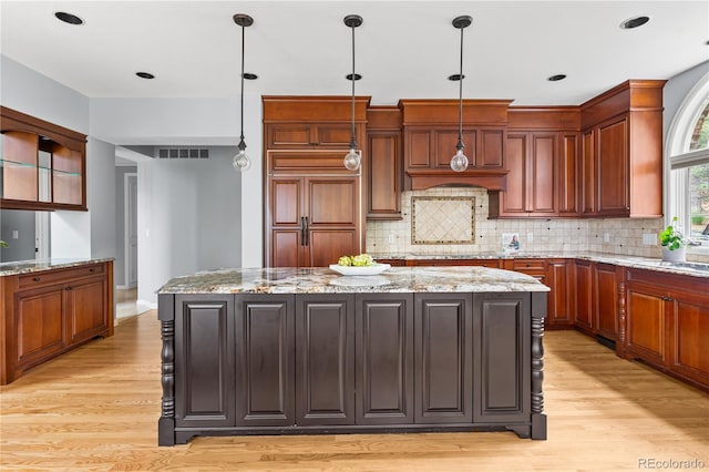 18963 E Long Ave, Centennial, CO 80016 - kitchen featuring light wood-style floors, a center island, decorative backsplash, pendant lighting, and light stone counters