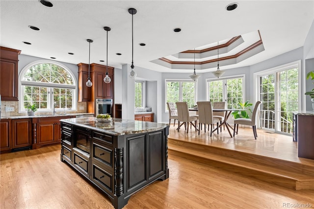 18963 E Long Ave, Centennial, CO 80016 - kitchen with stainless steel appliances, light wood-style floors, a raised ceiling, light stone countertops, and a kitchen island