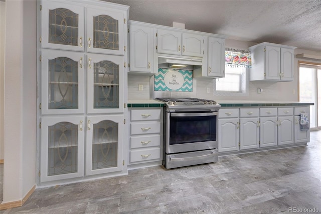 kitchen with stainless steel gas stove, white cabinetry, a wealth of natural light, and backsplash