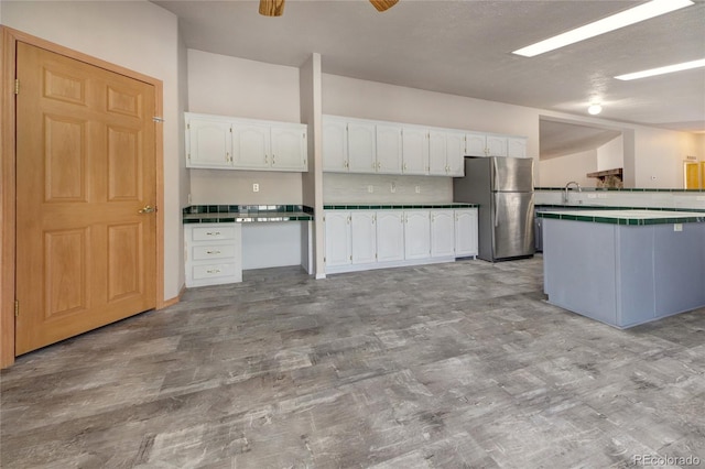 kitchen with decorative backsplash, ceiling fan, sink, white cabinetry, and stainless steel refrigerator