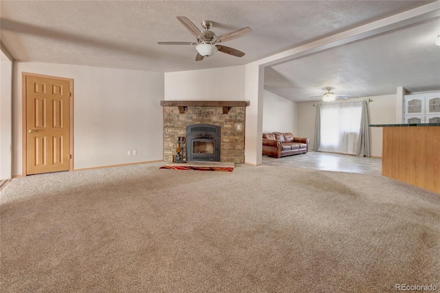 unfurnished living room with a stone fireplace, light colored carpet, and a textured ceiling