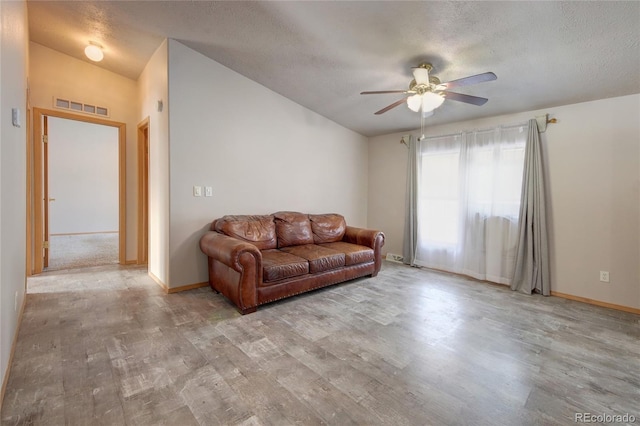 living room with lofted ceiling, ceiling fan, light hardwood / wood-style flooring, and a textured ceiling