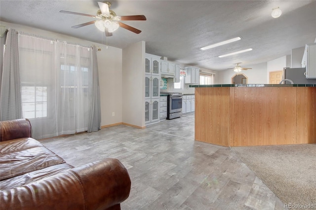 kitchen featuring kitchen peninsula, appliances with stainless steel finishes, a textured ceiling, white cabinets, and light hardwood / wood-style floors