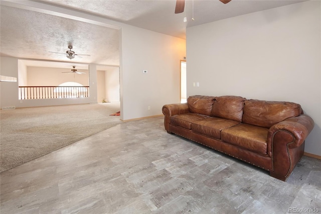 carpeted living room with ceiling fan and a textured ceiling