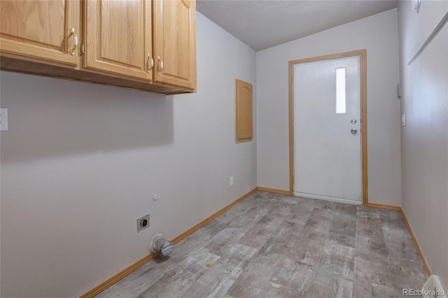 laundry area featuring electric dryer hookup, light hardwood / wood-style floors, cabinets, and a textured ceiling