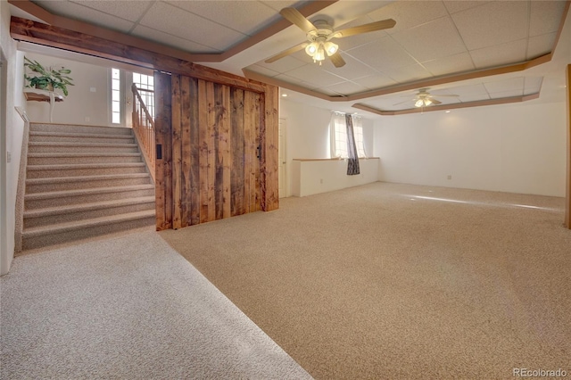 basement featuring carpet flooring, ceiling fan, a paneled ceiling, and plenty of natural light