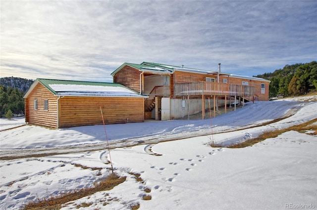 snow covered rear of property featuring a wooden deck