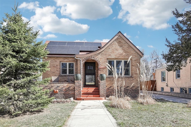 view of front of home featuring brick siding and roof mounted solar panels