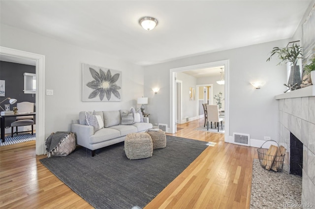 living area with visible vents, a fireplace, baseboards, and wood finished floors