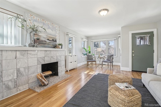 living room with baseboards, wood finished floors, and a tile fireplace