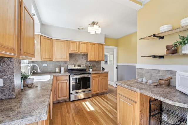 kitchen with a sink, tasteful backsplash, light wood-style flooring, and electric stove