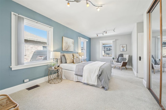 bedroom featuring visible vents, multiple windows, track lighting, and carpet flooring