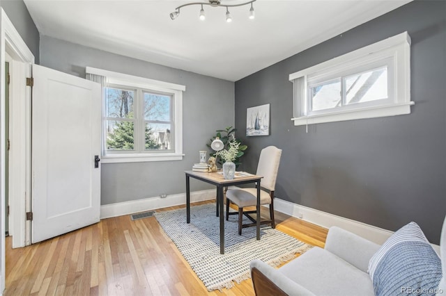 office space featuring light wood finished floors, visible vents, and baseboards