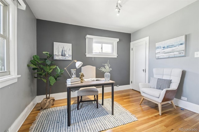 office space with track lighting, baseboards, and light wood-type flooring