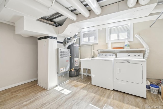 laundry room with laundry area, gas water heater, washing machine and dryer, and wood finished floors