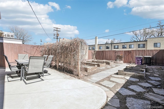 view of patio with a vegetable garden, outdoor dining area, and a fenced backyard