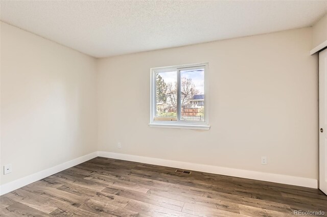 empty room featuring baseboards, visible vents, and wood finished floors