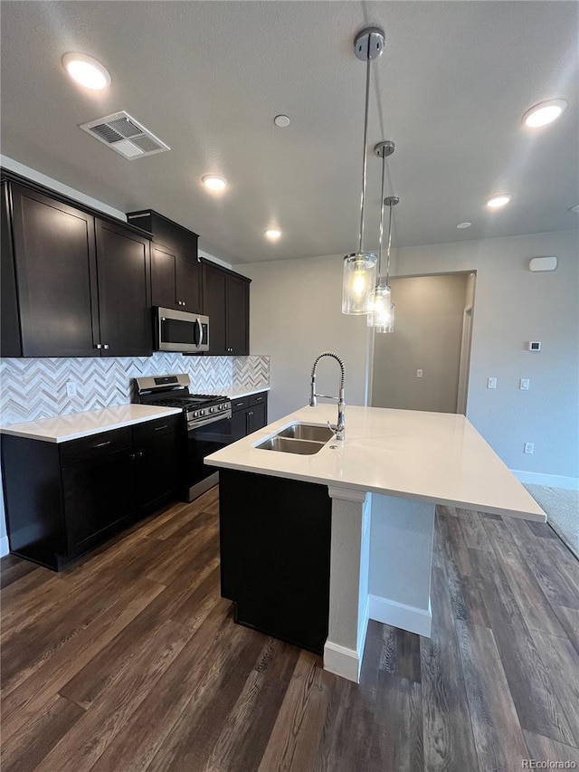 16841 Askins Loop Unit 208, Parker, CO 80134 - kitchen with dark wood-style flooring, appliances with stainless steel finishes, a sink, visible vents, and a center island with sink