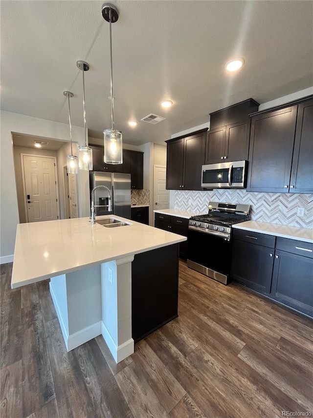 16841 Askins Loop Unit 208, Parker, CO 80134 - kitchen with visible vents, appliances with stainless steel finishes, tasteful backsplash, a sink, and an island with sink
