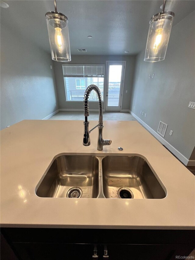 16841 Askins Loop Unit 208, Parker, CO 80134 - room details featuring visible vents, baseboards, light countertops, a sink, and decorative light fixtures