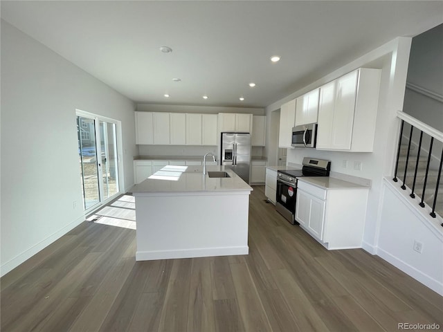 kitchen with white cabinets, dark wood-style floors, appliances with stainless steel finishes, light countertops, and a sink