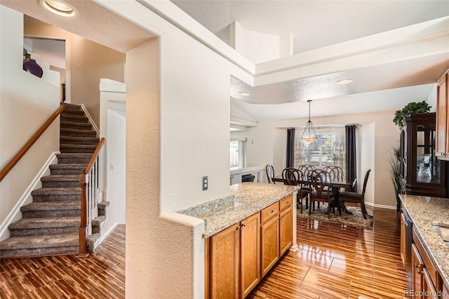 20336 E 48th Dr, Denver, CO 80249 - kitchen with light wood finished floors, light stone countertops, brown cabinets, pendant lighting, and baseboards