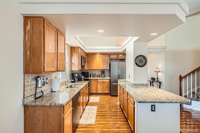 20336 E 48th Dr, Denver, CO 80249 - kitchen featuring appliances with stainless steel finishes, light wood-type flooring, a tray ceiling, a sink, and a center island