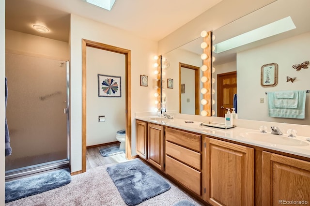 18150 Martingale Rd, Monument, CO 80132 - full bath featuring a skylight, double vanity, toilet, a shower stall, and wood finished floors