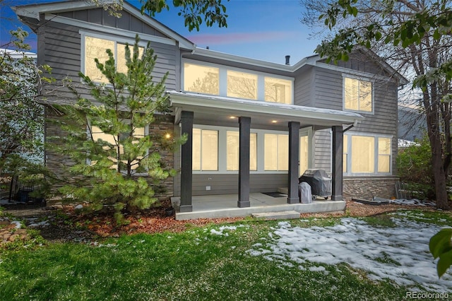 back of property featuring stone siding, board and batten siding, and a porch
