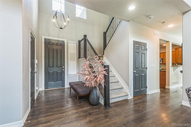 entryway with a chandelier, visible vents, wood finished floors, and stairs