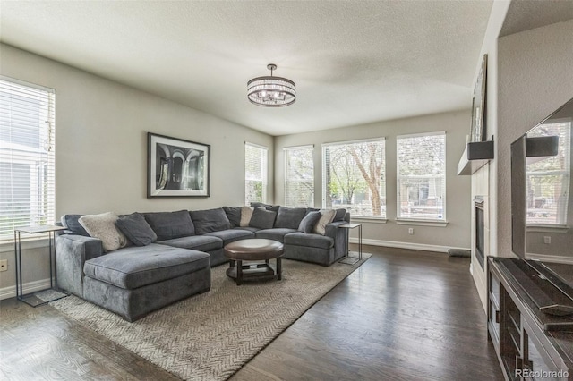 living room featuring plenty of natural light, a chandelier, baseboards, and dark wood-style floors