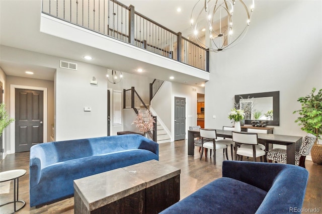 living room featuring visible vents, wood finished floors, a towering ceiling, and stairway