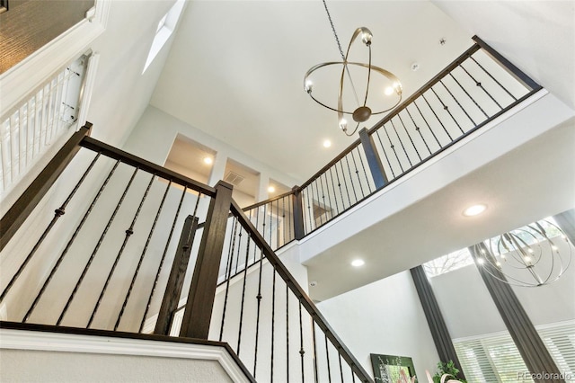 stairs featuring recessed lighting, an inviting chandelier, visible vents, and a towering ceiling