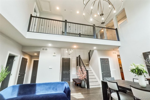 living room with a chandelier, visible vents, a high ceiling, and wood finished floors
