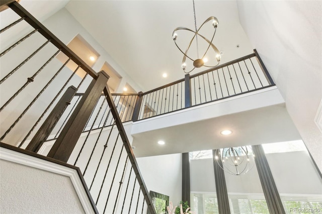stairway featuring an inviting chandelier, a high ceiling, and recessed lighting
