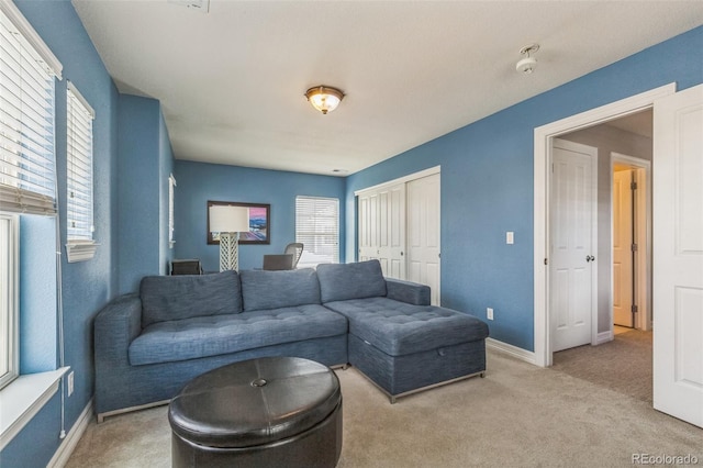 living room featuring baseboards and light colored carpet