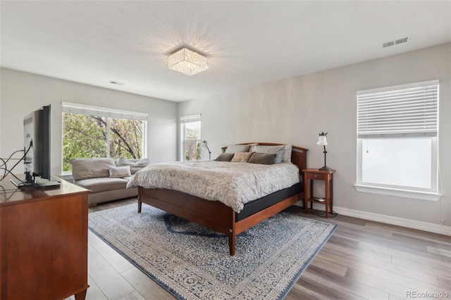 bedroom with baseboards, visible vents, and wood finished floors