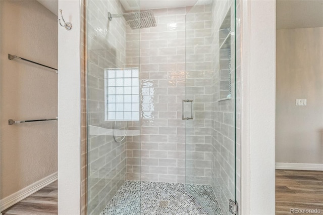bathroom featuring a stall shower, baseboards, and wood finished floors