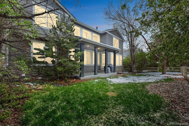 rear view of property featuring covered porch and a yard
