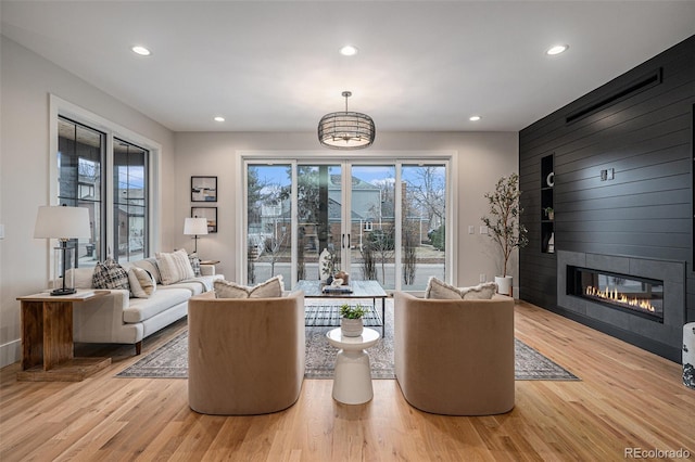 living room with a fireplace, light hardwood / wood-style floors, and an inviting chandelier