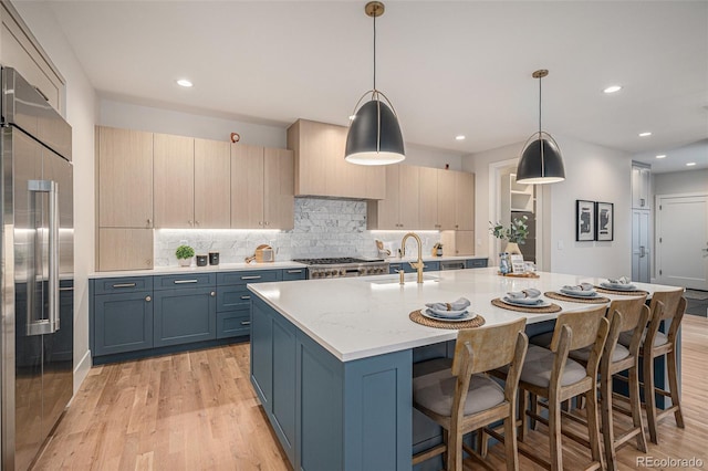 kitchen with decorative light fixtures, stainless steel built in fridge, light stone countertops, and sink