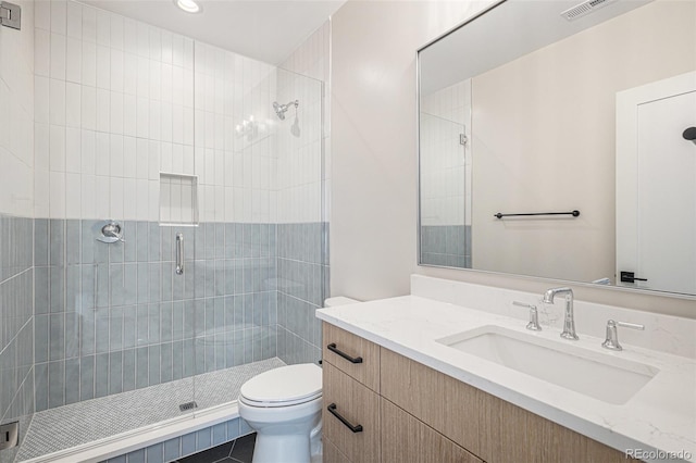 bathroom featuring a shower with door, vanity, and toilet