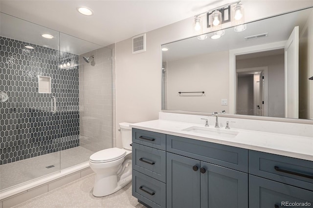 bathroom with tile patterned flooring, a tile shower, vanity, and toilet