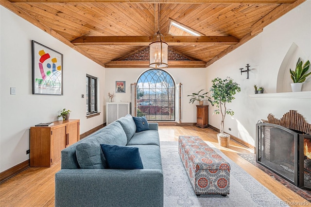 living room with baseboards, lofted ceiling with beams, wood ceiling, light wood-type flooring, and a chandelier