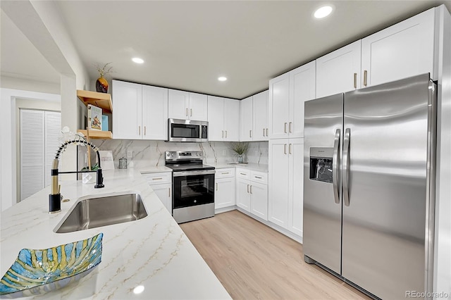 kitchen featuring white cabinets, sink, light stone counters, and stainless steel appliances