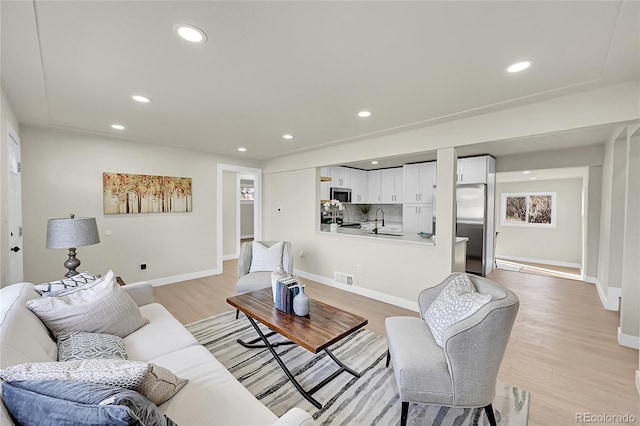 living room with light hardwood / wood-style flooring and sink