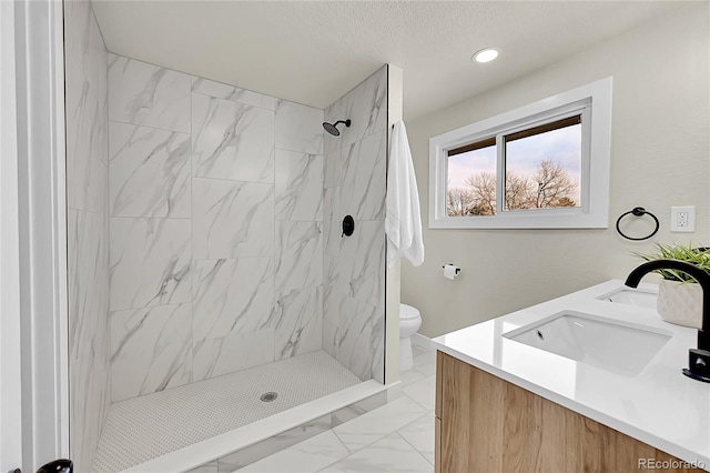 bathroom with vanity, toilet, and a tile shower