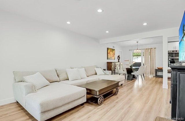 living room with an inviting chandelier and light wood-type flooring