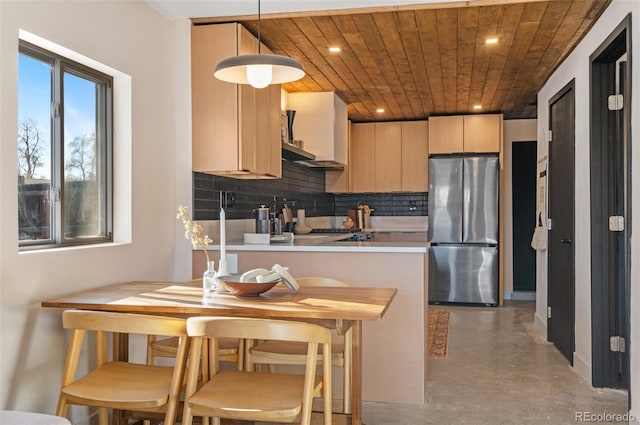 kitchen with pendant lighting, stainless steel refrigerator, backsplash, light brown cabinets, and wooden ceiling