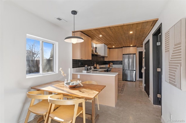 kitchen featuring light brown cabinetry, wood ceiling, stainless steel refrigerator, kitchen peninsula, and decorative backsplash